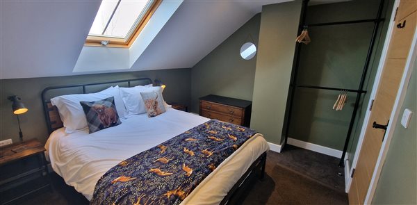 1st floor king, metal framed bed, an open wardrobe, skylight over the bed and chest of drawers